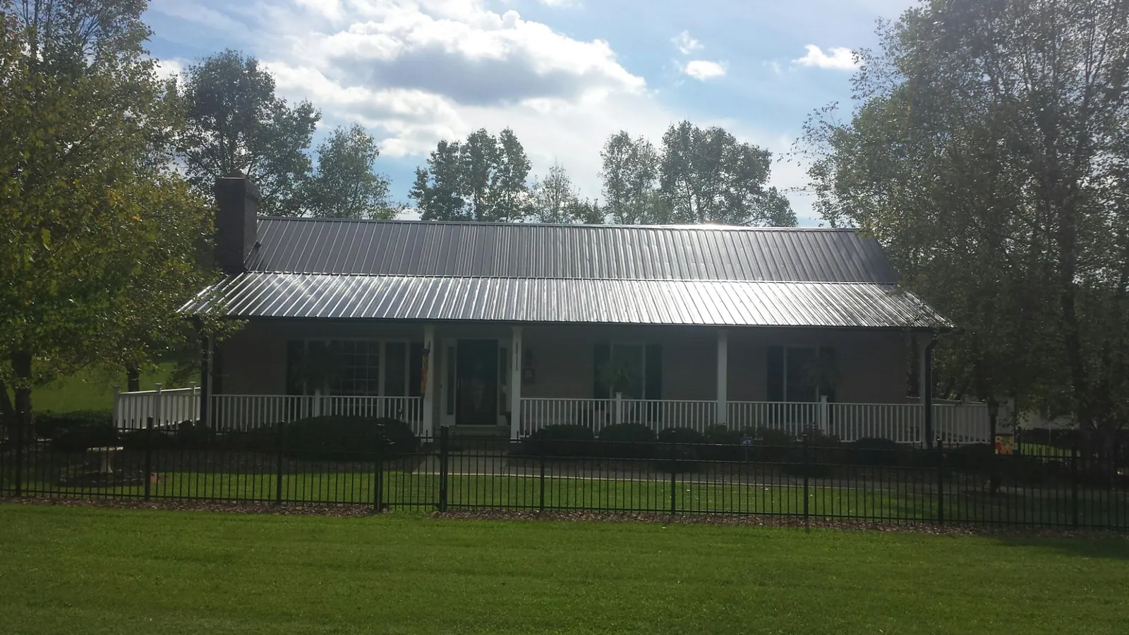 Gray metal roof on a brick ranch with a full width front porch — Gutter Guard Installation work by our crew in Boone