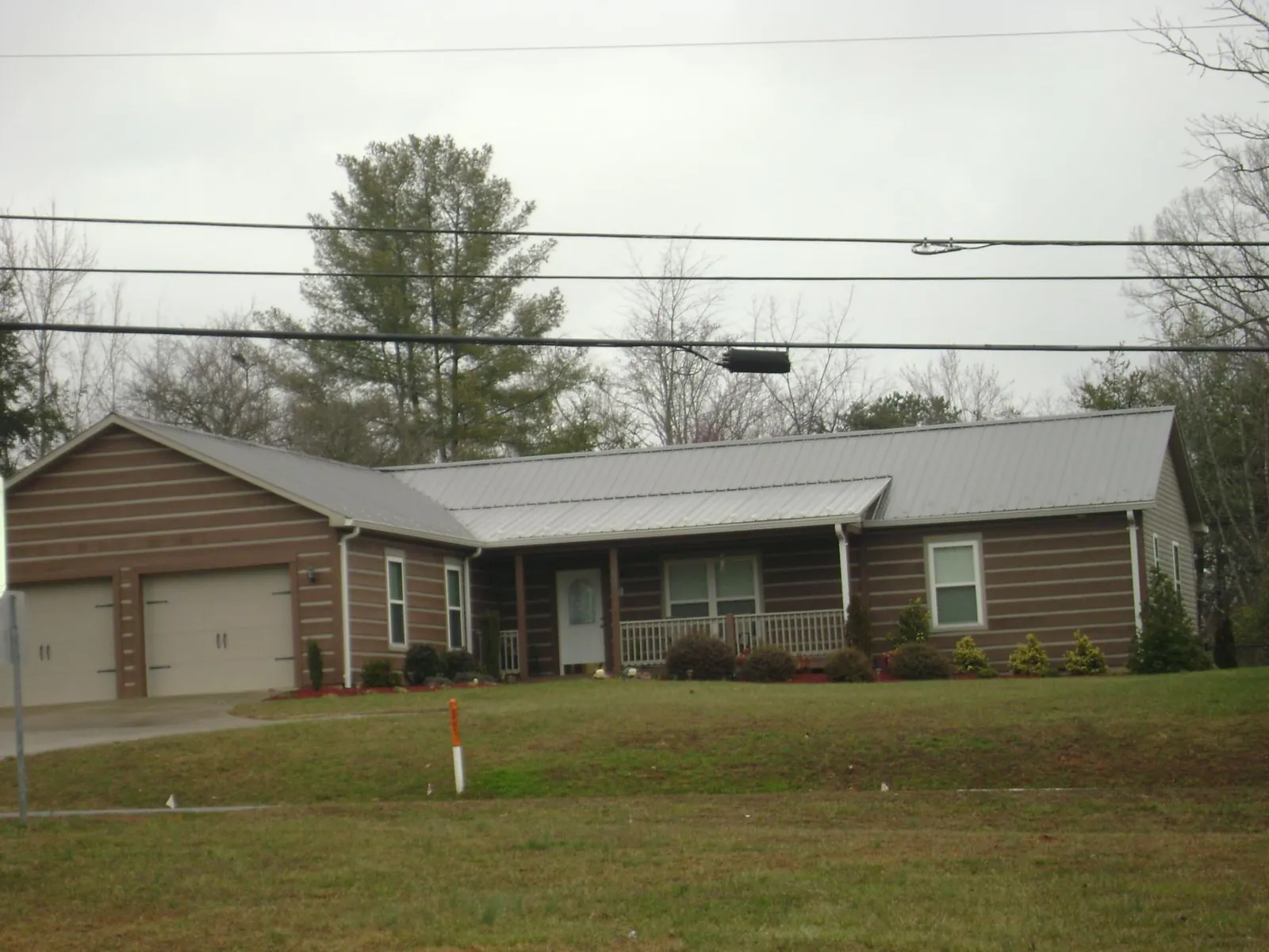 Gray metal roof on a log sided ranch home with a front porch in Boone