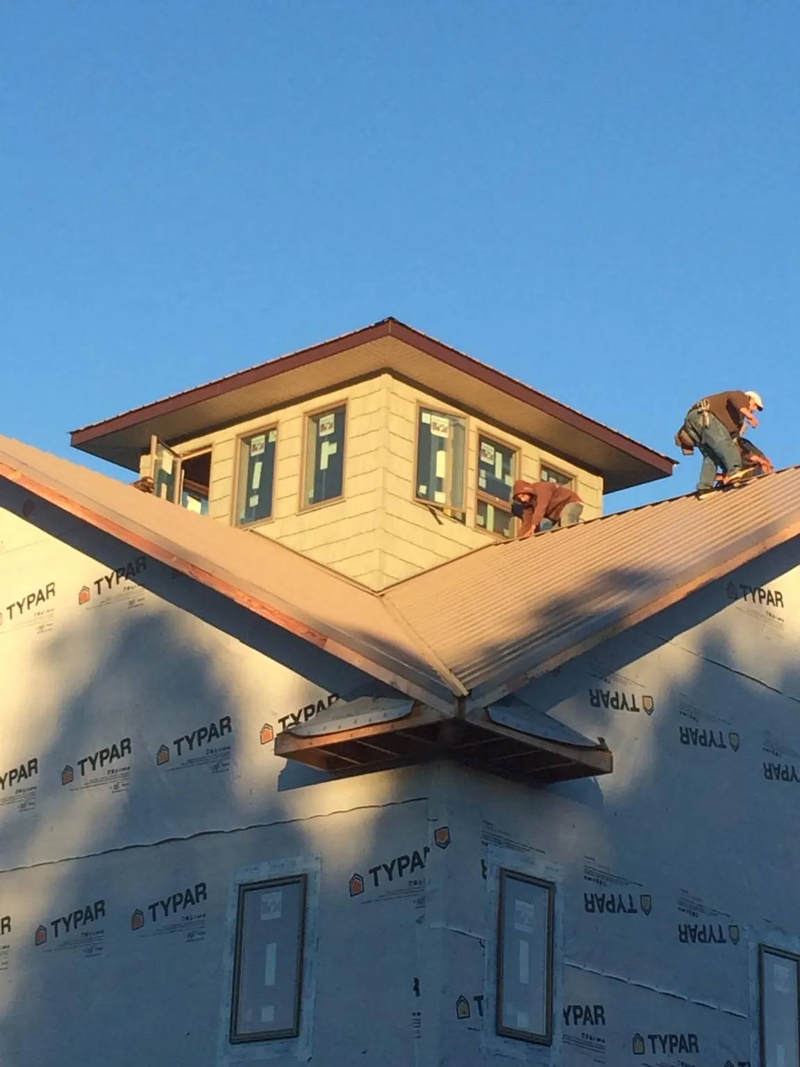 Roofers working around a rooftop cupola on a new metal roof at sunset — Roof Waterproofing in Boone by Roofing Brothers